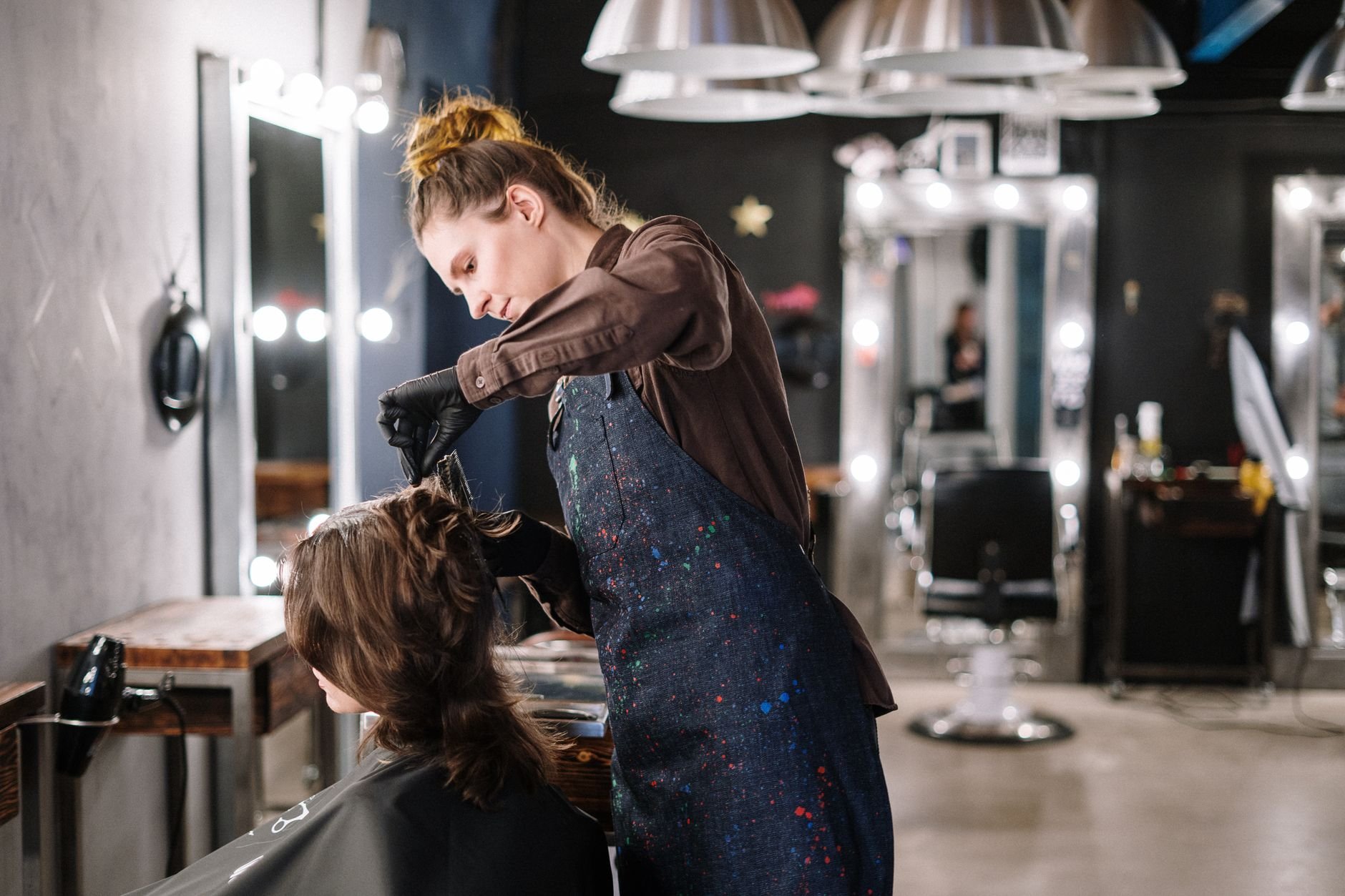 A female stylist applying hair colour to a client in a modern salon